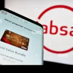 Smartphone displaying an Absa banking webpage in front of a large Absa logo, representing Absa digital banking, financial services and investor-facing transparency.