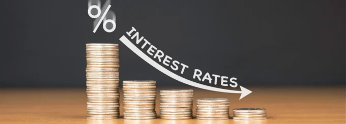 Stacks of coins with a downward arrow labelled interest rates, representing fixed deposit rates, savings returns, and interest-rate movement.