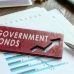 Government bonds label placed on financial charts with a pen and calculator, representing bond yields, auction pricing, and fixed-income investment analysis.