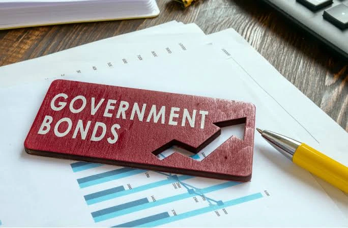 Government bonds label placed on financial charts with a pen and calculator, representing bond yields, auction pricing, and fixed-income investment analysis.