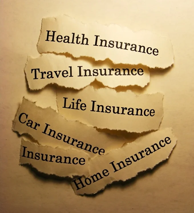 Torn paper labels showing health insurance, travel insurance, life insurance, car insurance, and home insurance, representing insurance products and policyholder protection.