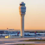 Wide airport image showing a control tower, runways, aircraft and terminal infrastructure at sunset, representing Atlanta airport operations and the aviation infrastructure behind an airport revenue bond financing.