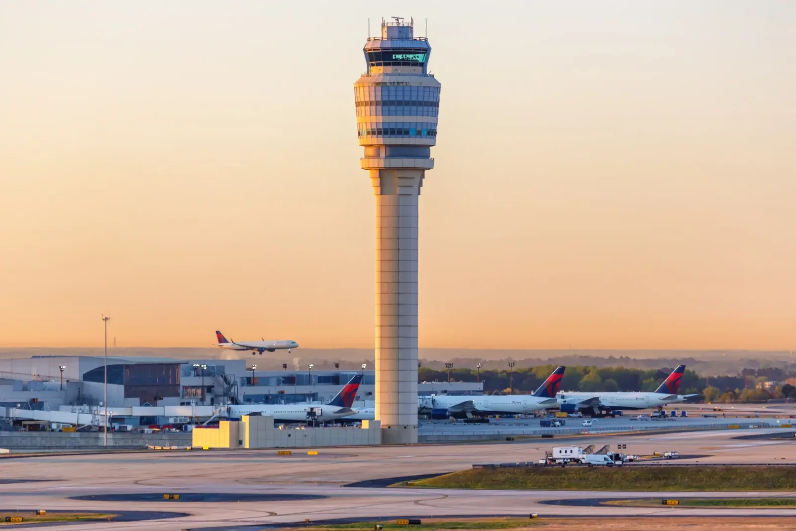 Wide airport image showing a control tower, runways, aircraft and terminal infrastructure at sunset, representing Atlanta airport operations and the aviation infrastructure behind an airport revenue bond financing.