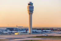 Wide airport image showing a control tower, runways, aircraft and terminal infrastructure at sunset, representing Atlanta airport operations and the aviation infrastructure behind an airport revenue bond financing.