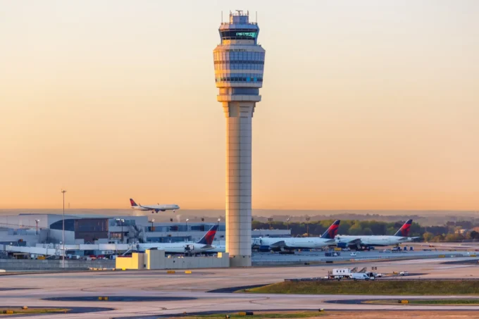 Wide airport image showing a control tower, runways, aircraft and terminal infrastructure at sunset, representing Atlanta airport operations and the aviation infrastructure behind an airport revenue bond financing.