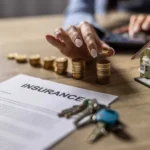 Insurance policy document with coins, keys and a model home, representing claim protection, insurer failure risk, compensation payouts and policyholder financial security.