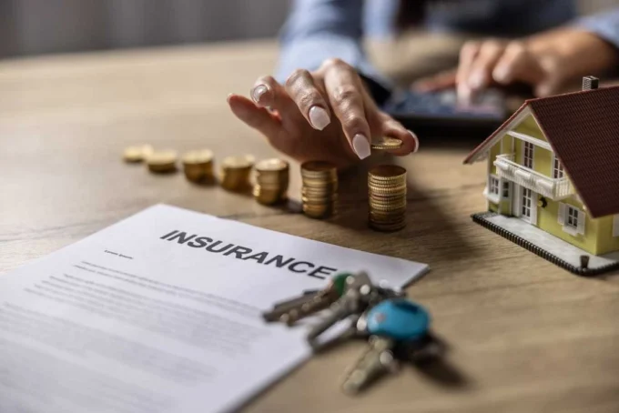 Insurance policy document with coins, keys and a model home, representing claim protection, insurer failure risk, compensation payouts and policyholder financial security.