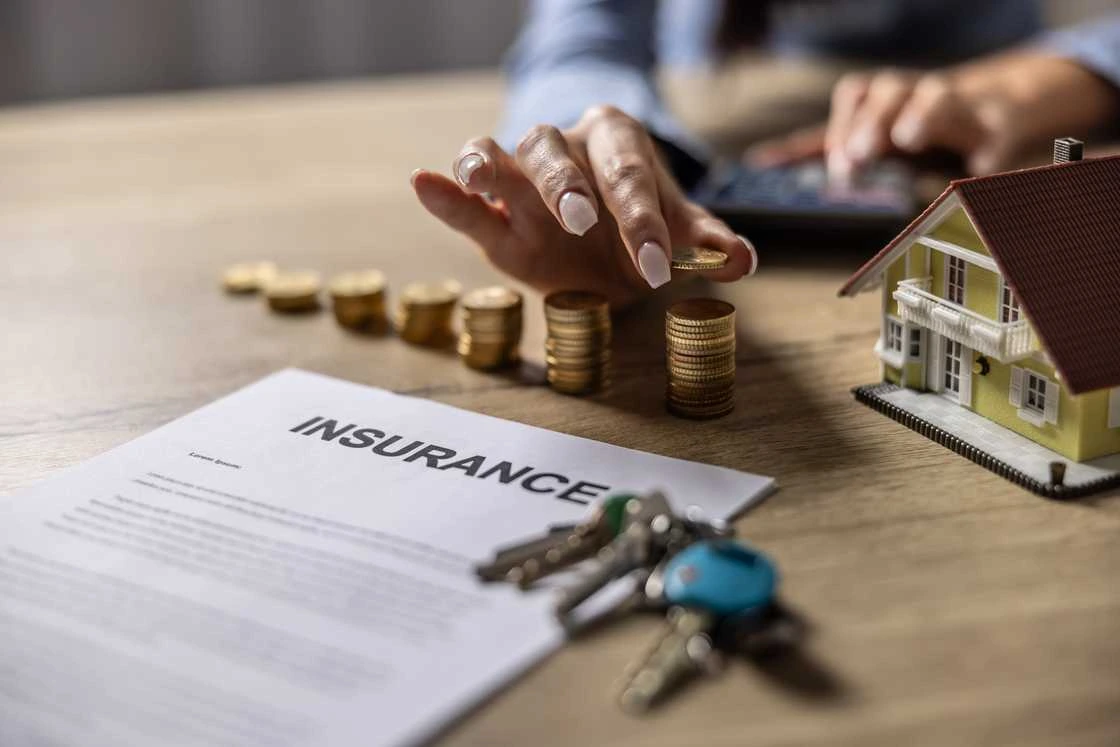 Insurance policy document with coins, keys and a model home, representing claim protection, insurer failure risk, compensation payouts and policyholder financial security.