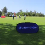 Article image showing a golf course in Kenya with a Liberty and Heritage Insurance branded sign in the foreground and several people standing on the course in the distance. The image represents Liberty Kenya’s insurance brand presence and can be used as a contextual visual for an article about Liberty Kenya, LifeVest, investment-linked insurance and policyholder protection.