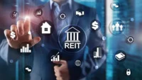 Businessperson interacting with digital REIT icons showing property, income, cash flow, investors and real estate investment assets.