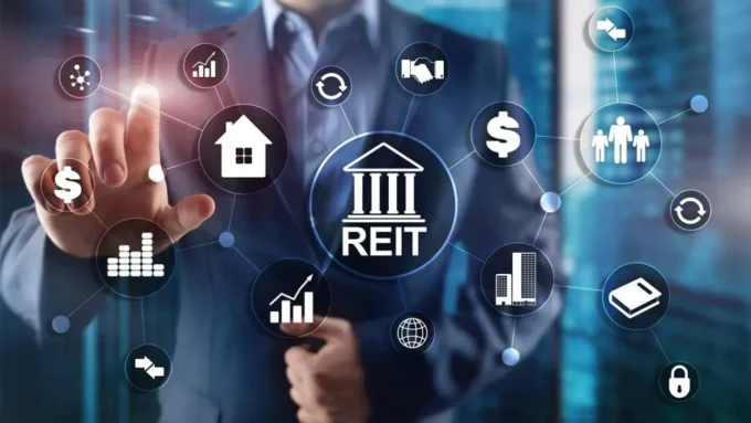 Businessperson interacting with digital REIT icons showing property, income, cash flow, investors and real estate investment assets.