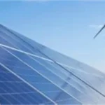 Solar panels in the foreground with a wind turbine in the background under a blue sky, representing renewable energy, clean-power infrastructure, climate finance and green-bond investment projects.